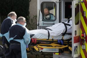 2 medics load a stretcher with a patient into an ambulance